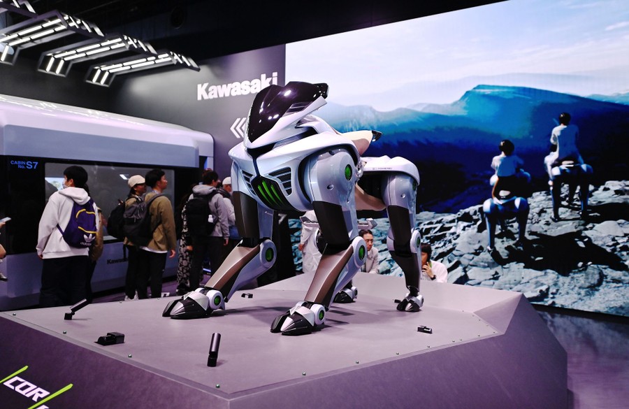 People walk past a concept model of a four-legged rideable robot.