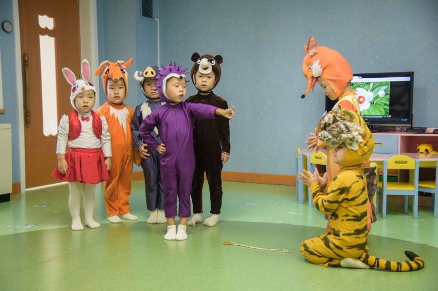 Seven children in costumes perform a play in a classroom.