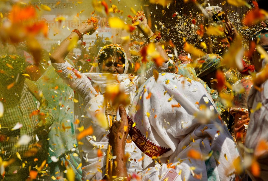People dance while throwing colorful flower petals in the air.