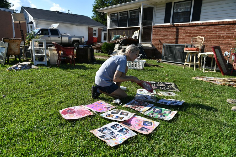 A person lays out flood-damaged scrapbook pages on a lawn.