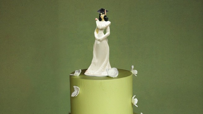 Figurine of a bride wearing a mortarboard on the top tier of a wedding cake, her groom seated on a tier below