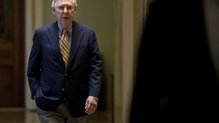 Mitch McConnell walks through a hallway.