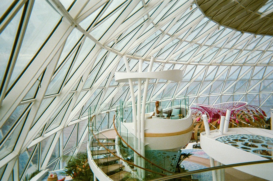 photo from inside of spacious geodesic-style glass dome facing ocean, with stairwells and seating areas