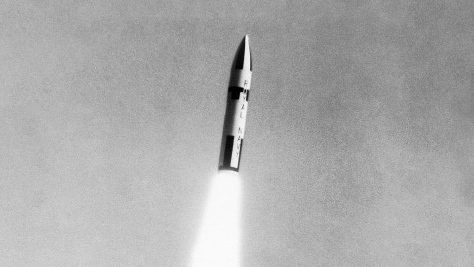 A black-and-white photo of a missile blasting upwards through the air with flames propelling it toward its target