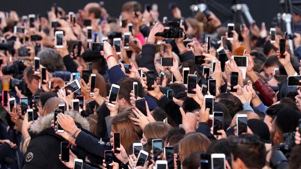 A crowd of people taking photos with smartphones