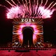 Fireworks erupt from the top of the Arc de Triomphe in Paris, with the number "2024" painted on it in light.
