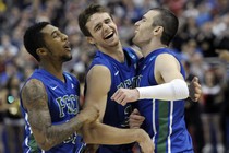 Three basketball players hug and smile