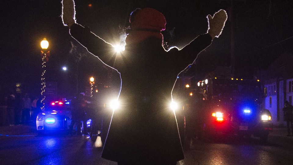 A protester raises her hands while blocking police cars