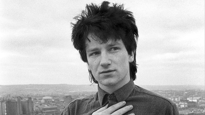 black-and-white photo of Bono with hand to chest