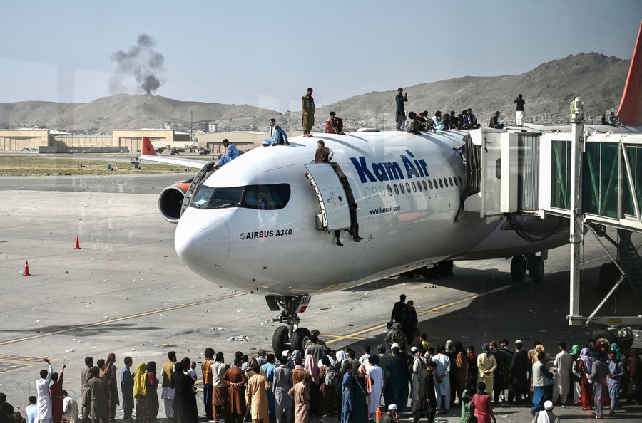 Dozens of people stand below, in, and on a commercial airliner parked at an airport.