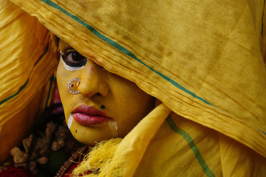 A woman wears yellow makeup on her face, and covers her head with yellow cloth.