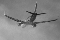 A black and white photo of a Southwest airplane taking off through low clouds