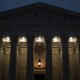 Photograph of the Supreme Court building at dusk with a hanging lantern and lights illuminating the entrance