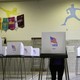 A woman stands at one of many polling booths inside an elementary-school gymnasium.