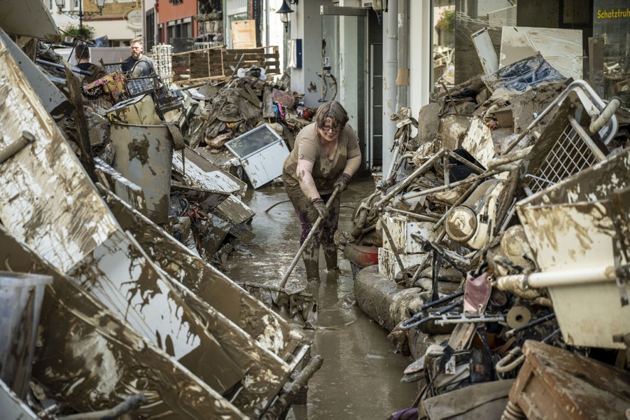 People clean debris and mud from a street.