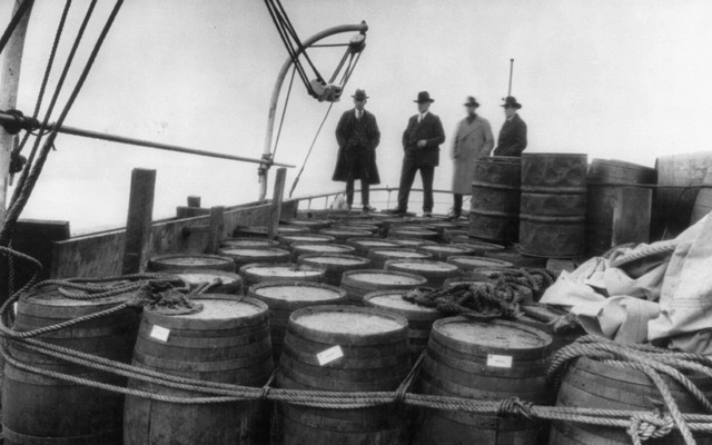 Prohibition agents examining barrels on boat, c. 1925.