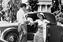 Black-and-white photo of a man helping a woman out of a car