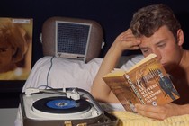 A young man reads a book at night.