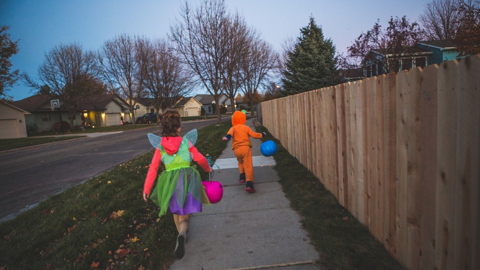 A girl and a boy in Halloween costumes run down an empty sidewalk