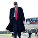 Donald Trump walks away from an airplane that reads "Trump."