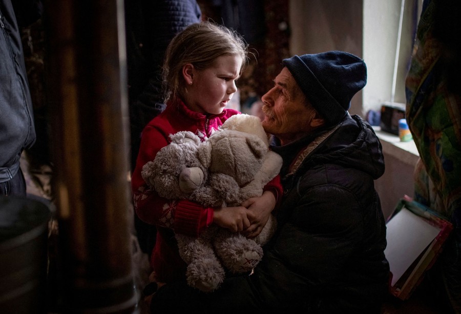 A man hugs his granddaughter as she holds several stuffed animals.