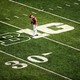 A football player walking across a football field.