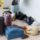 people sprawled out on an airport floor, along with carry-on suitcases