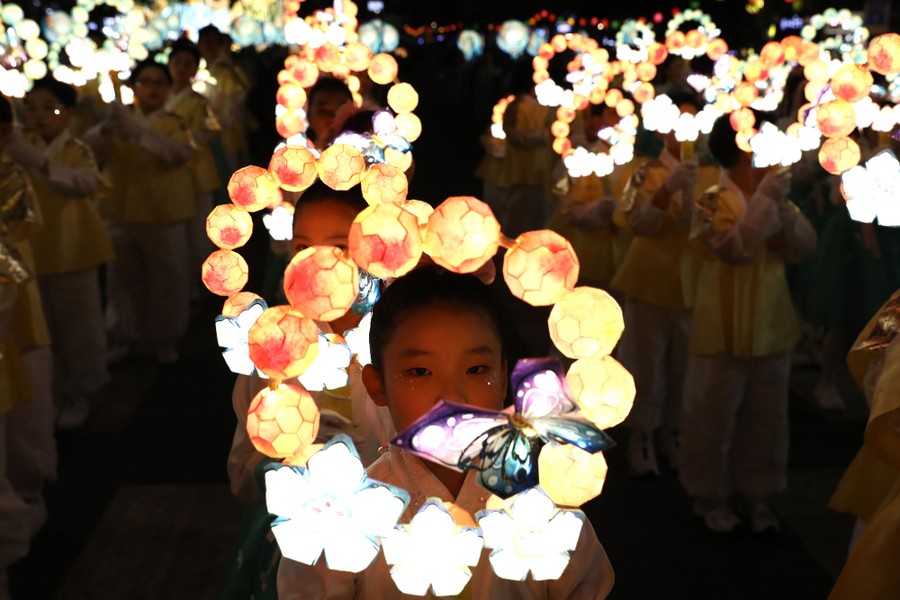 Young people carry illuminated lanterns in a processsion.