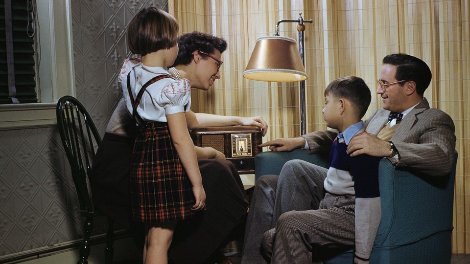 A family sits together listening to the radio.