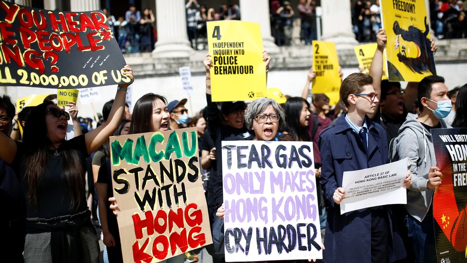 Supporters of the Hong Kong protests hold signs reading "Macau stands with Hong Kong" and "Tear gas only makes Hong Kong cry harder."