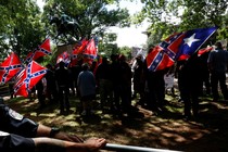 A group surrounds a statue while carrying Confederate flags.