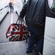 A man carries a bag with the British flag onto a bus.