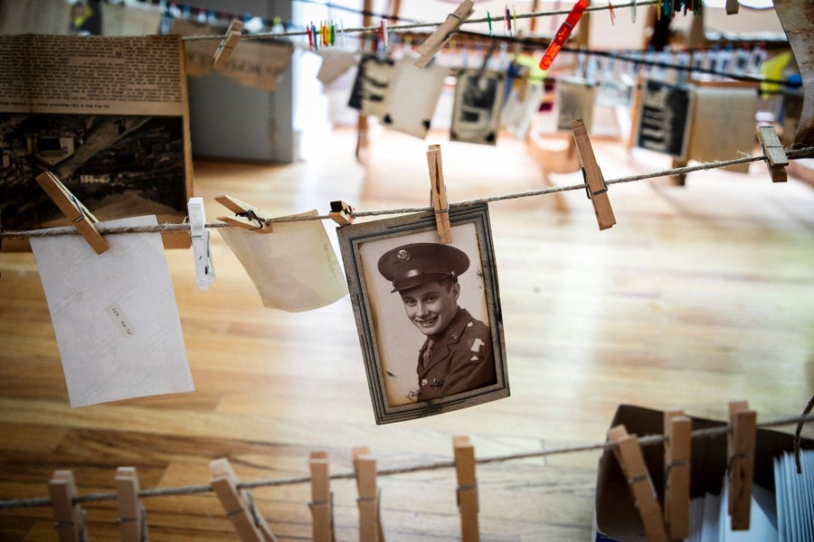 Old photographs hang from clothespins on lines inside a school building.