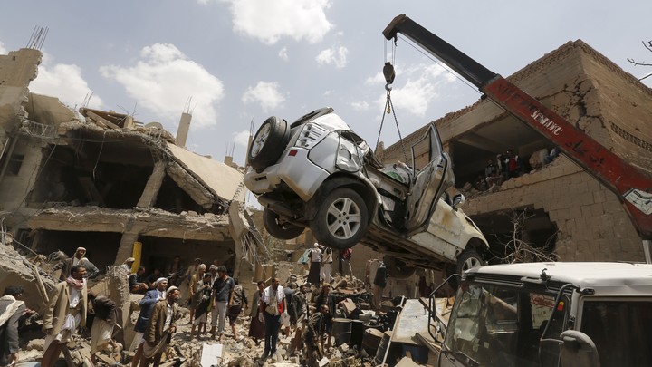 A car is lifted by a crane at the site of a Saudi-led air strike in Yemen's capital Sanaa.