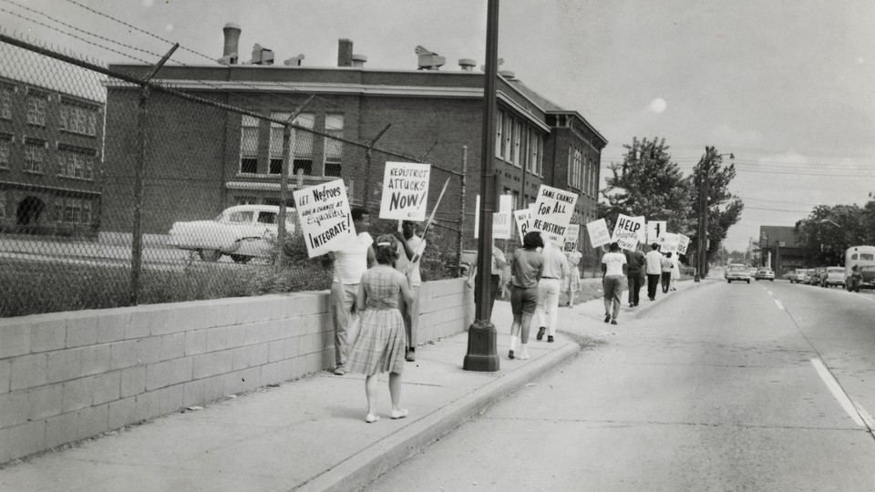 Protestors carried signs asking for school redistricting and integration. They were on the sidewalk in front of IPS School 17 in the 1960s.