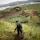 Photo of a Congolese soldier patrolling a hillside covered in vegetation