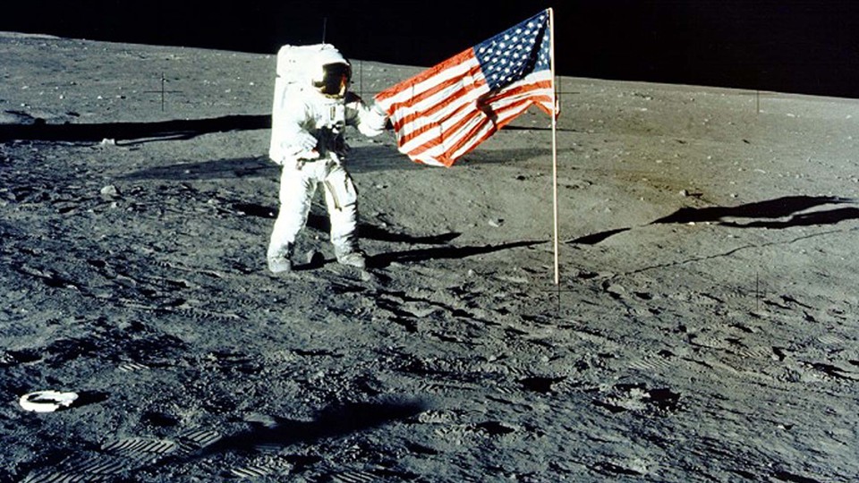 Charles "Pete" Conrad Jr. stands with the U.S. flag on the lunar surface during the Apollo 12 mission in 1969.