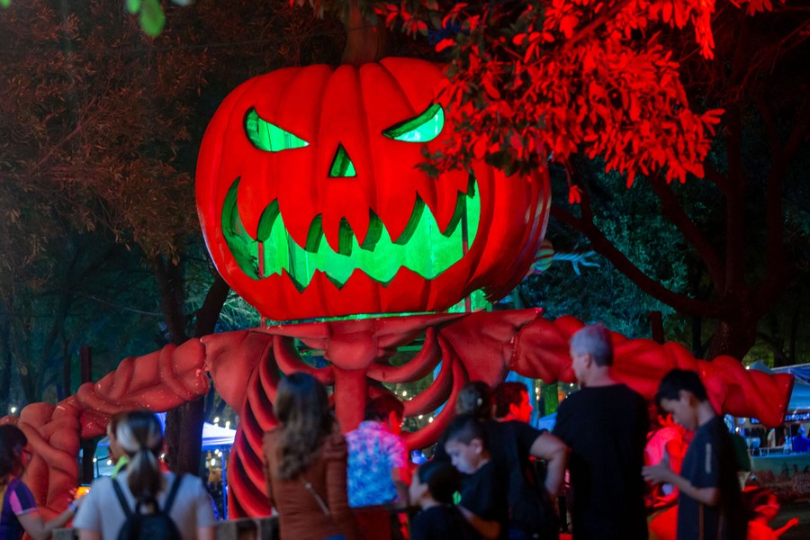 People stand near a giant illuminated jack-o'-lantern figure.