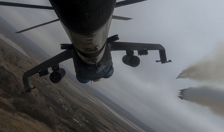 A view from a camera attached to the underside of a helicopter, as it fires missiles while flying above fields