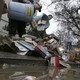 Workers dump recycling bins full of books and magazines on the ground.