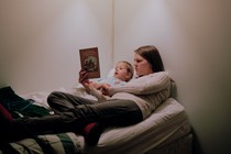 A mother reads 'Frog and Toad' with a toddler in bed