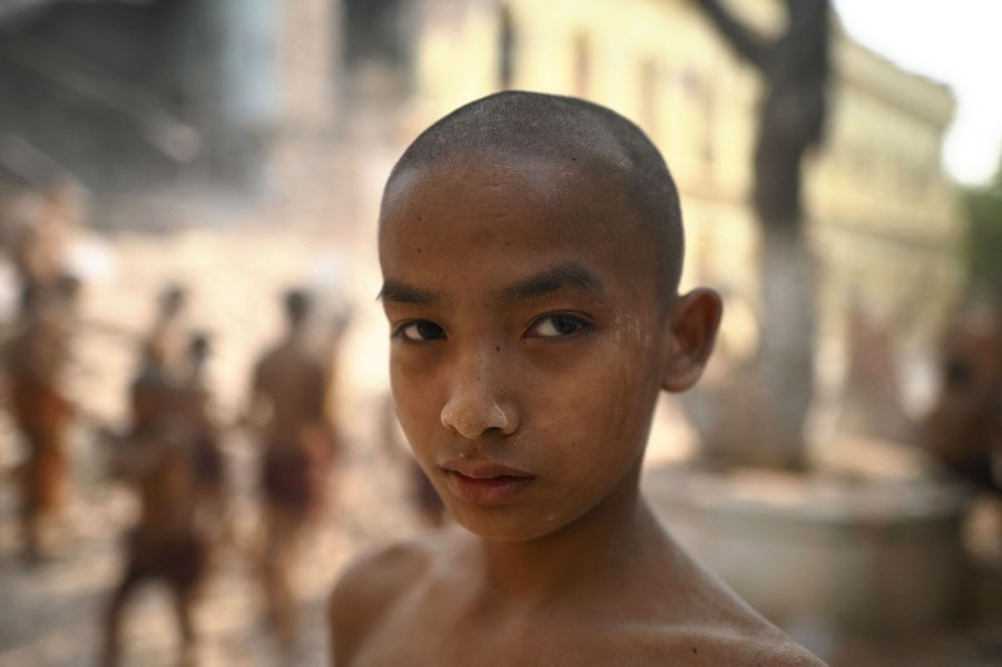 A young Buddhist monk looks toward the camera.