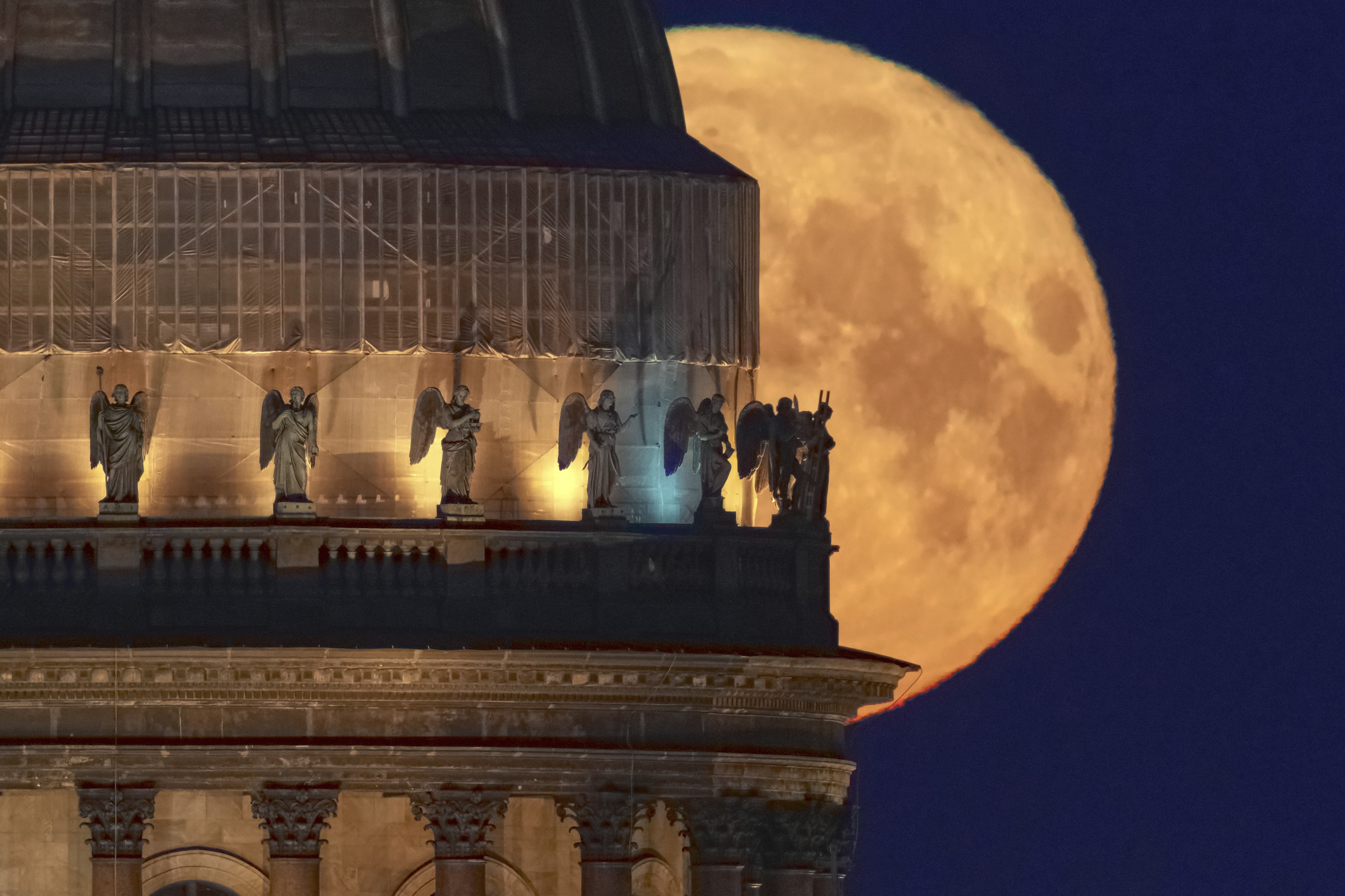 The full moon sets behind a cathedral.