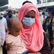 A photograph of a mask-wearing woman carrying a child.