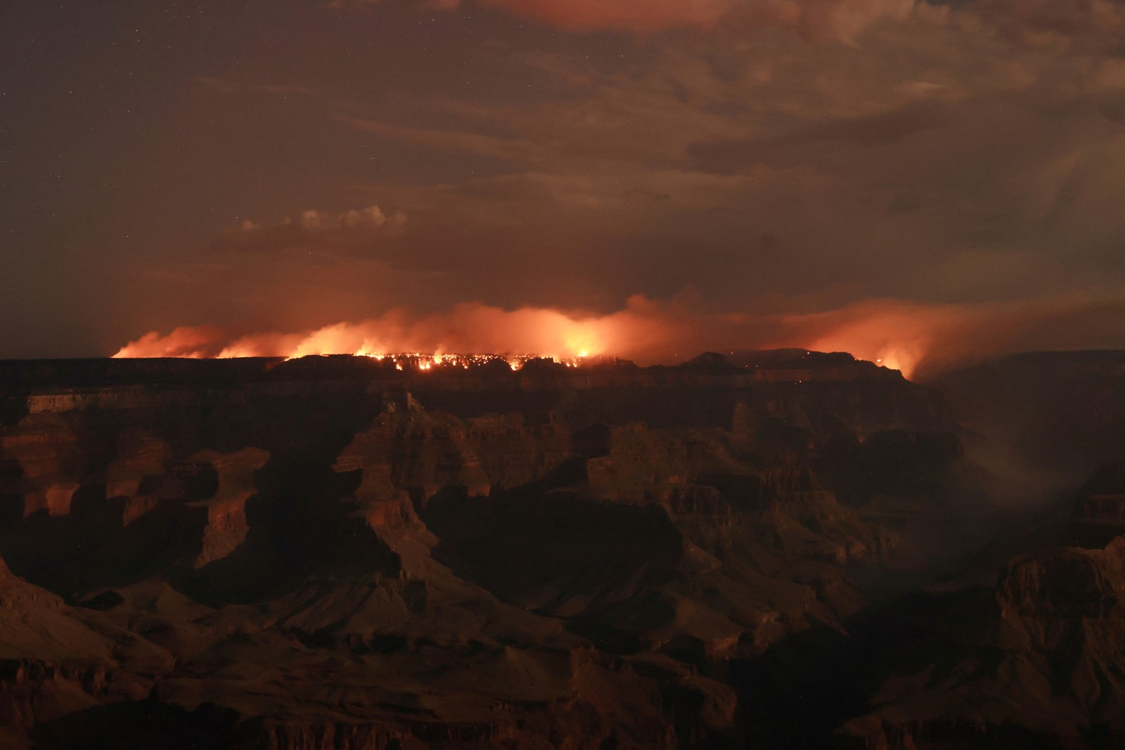A broad nighttime view of a wildfire burning along the Grand Canyon
