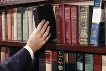 A hand pulling a book from a shelf