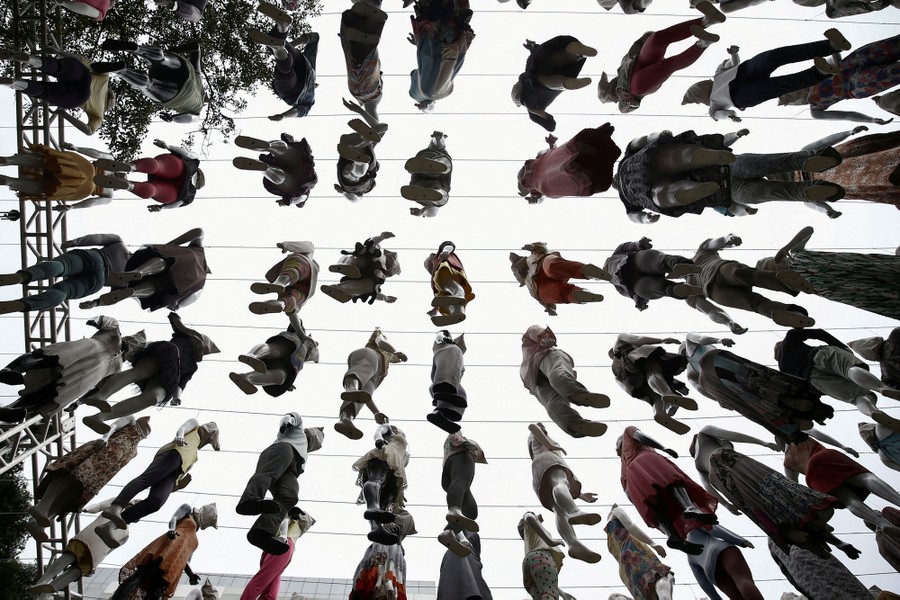 A view looking up at dozens of mannequins hanging from wires high overhead.
