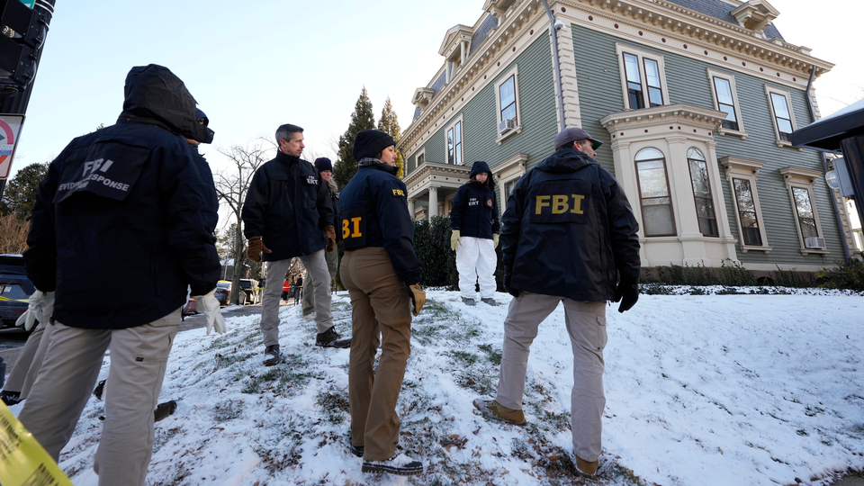 Photograph of several FBI agents standing in the snowy front yard of a green and white house.