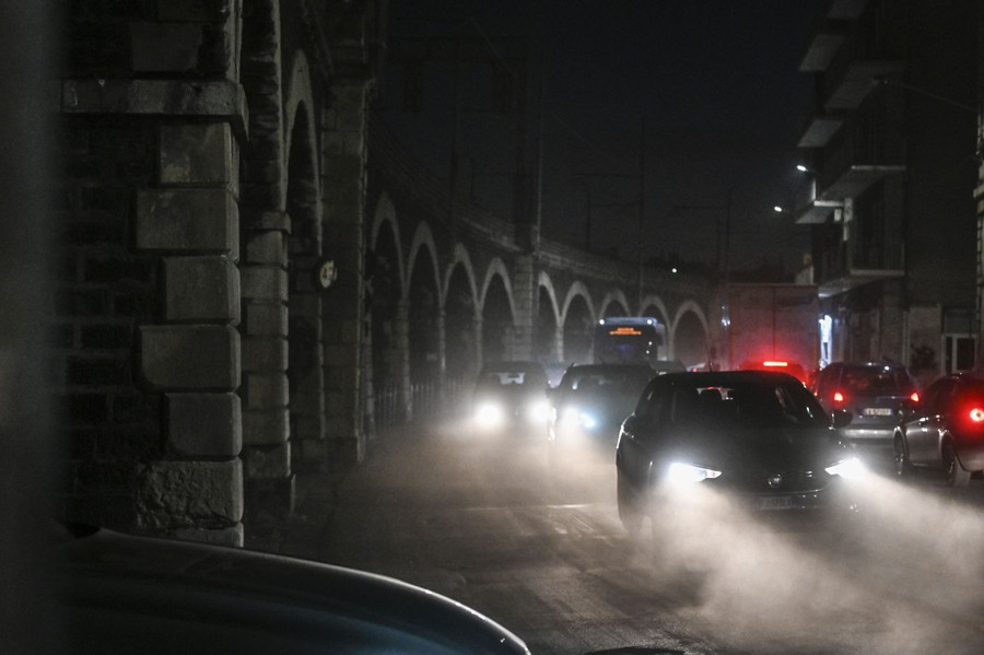 Cars drive at night on dusty streets.