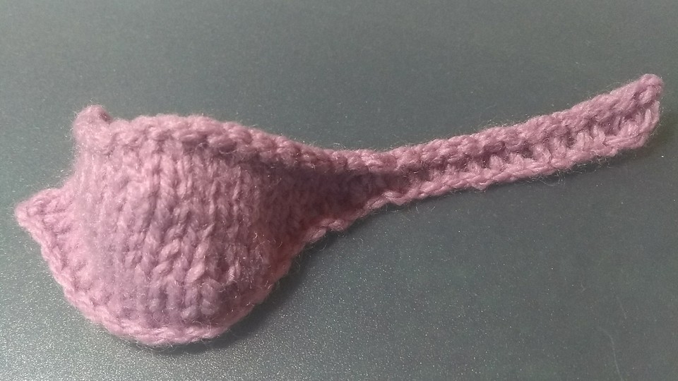 A pink knitted object resembling a ladle